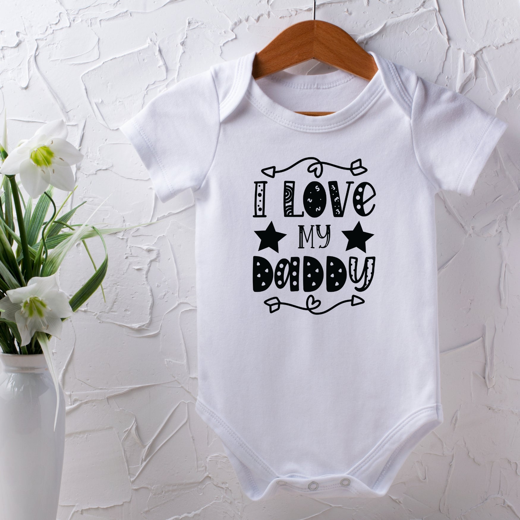 White baby onesie with 'I Love My Daddy' text on a textured white background. Gifts for dad. Stocking Filler